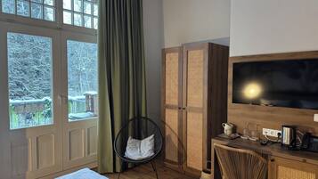 Una habitación de hotel con cama, escritorio con televisor, silla y armario.