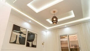 Un soggiorno moderno con divano, cuscini decorativi, arte astratta alle pareti e un lampadario.