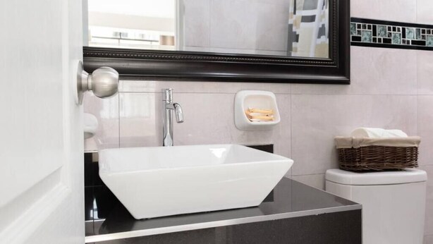 A modern bathroom with a white sink, a mirror, and a soap dispenser. - Residencial Suiza (Lima)
