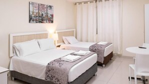 A hotel room with two beds, a small table, and a chair. - Residencial Suiza (Lima)