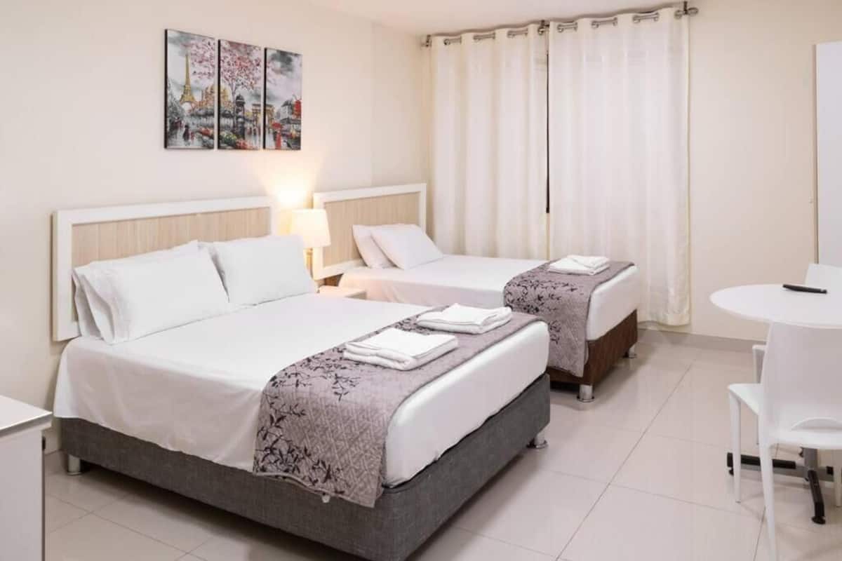 Ein Hotelzimmer mit zwei Betten, einem kleinen Tisch und einem Sessel.