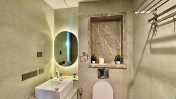 Ein modernes Badezimmer mit Waschbecken, Spiegel, Toilette und Dusche.