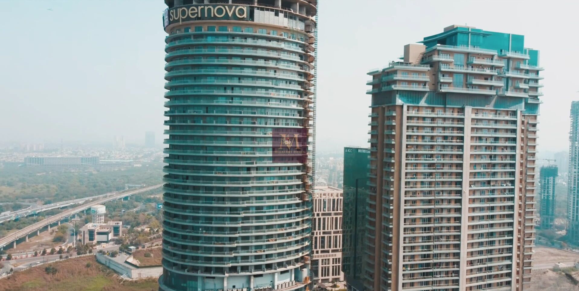 Dos edificios altos con un diseño arquitectónico moderno, con varios balcones y un letrero llamativo en el edificio de la izquierda.