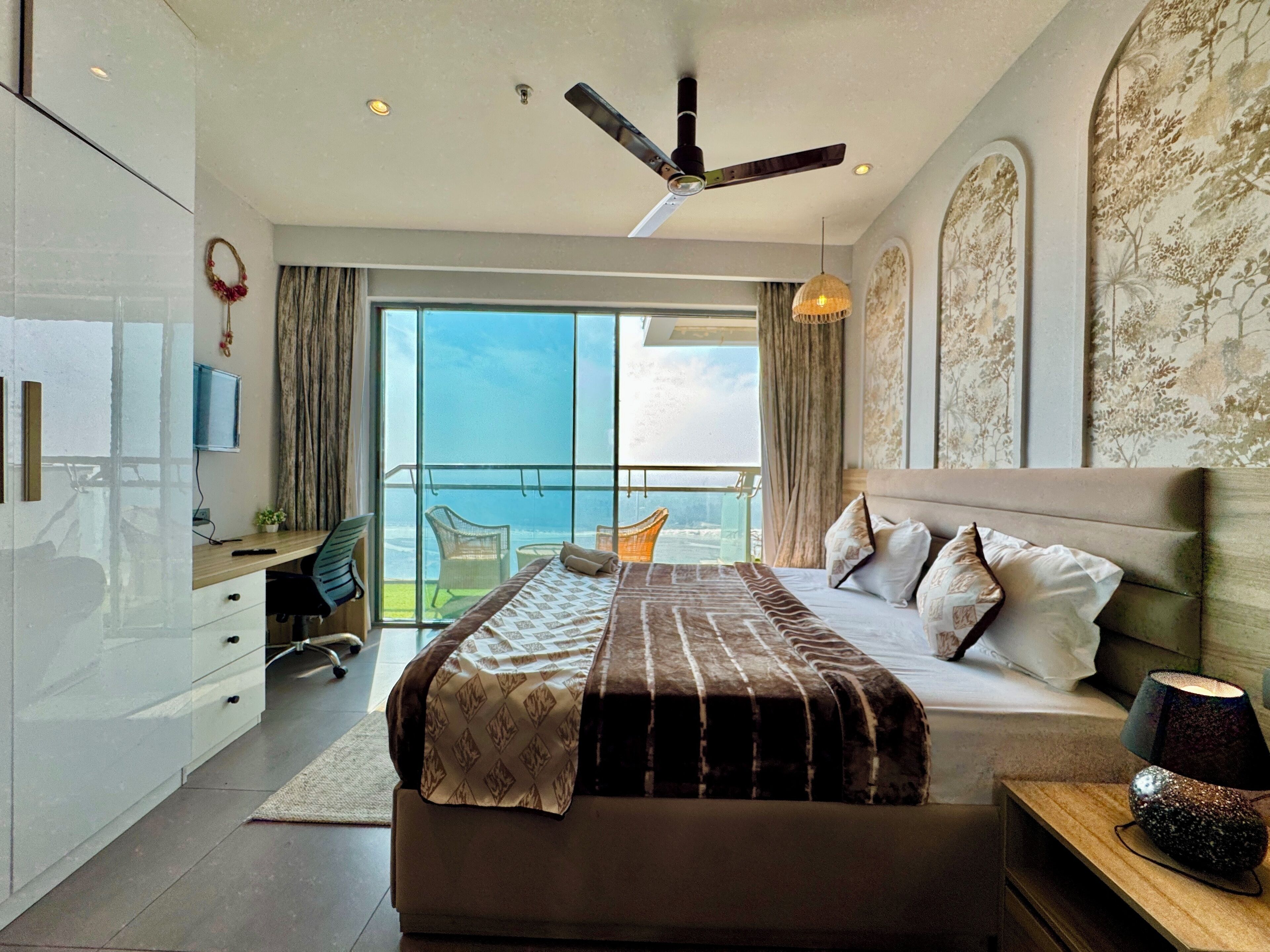 Una habitación de hotel moderna con una cama grande, un escritorio y un balcón con vistas.
