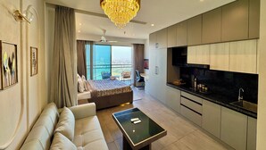 Une chambre d’hôtel moderne dotée d’un grand lit, d’un canapé, d’une table à manger, d’un coin cuisine et d’un balcon avec vue.