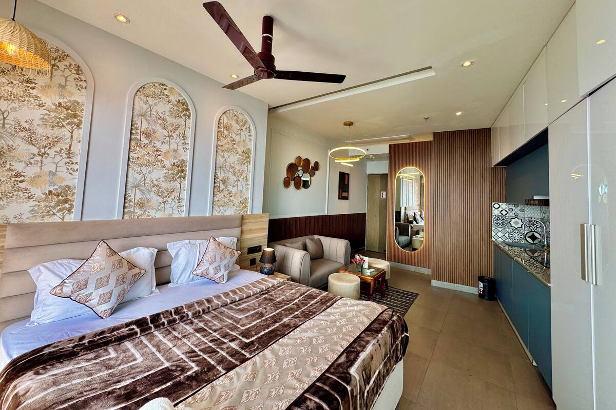 A modern bedroom with a large bed, a ceiling fan, and a view into the adjacent living area.