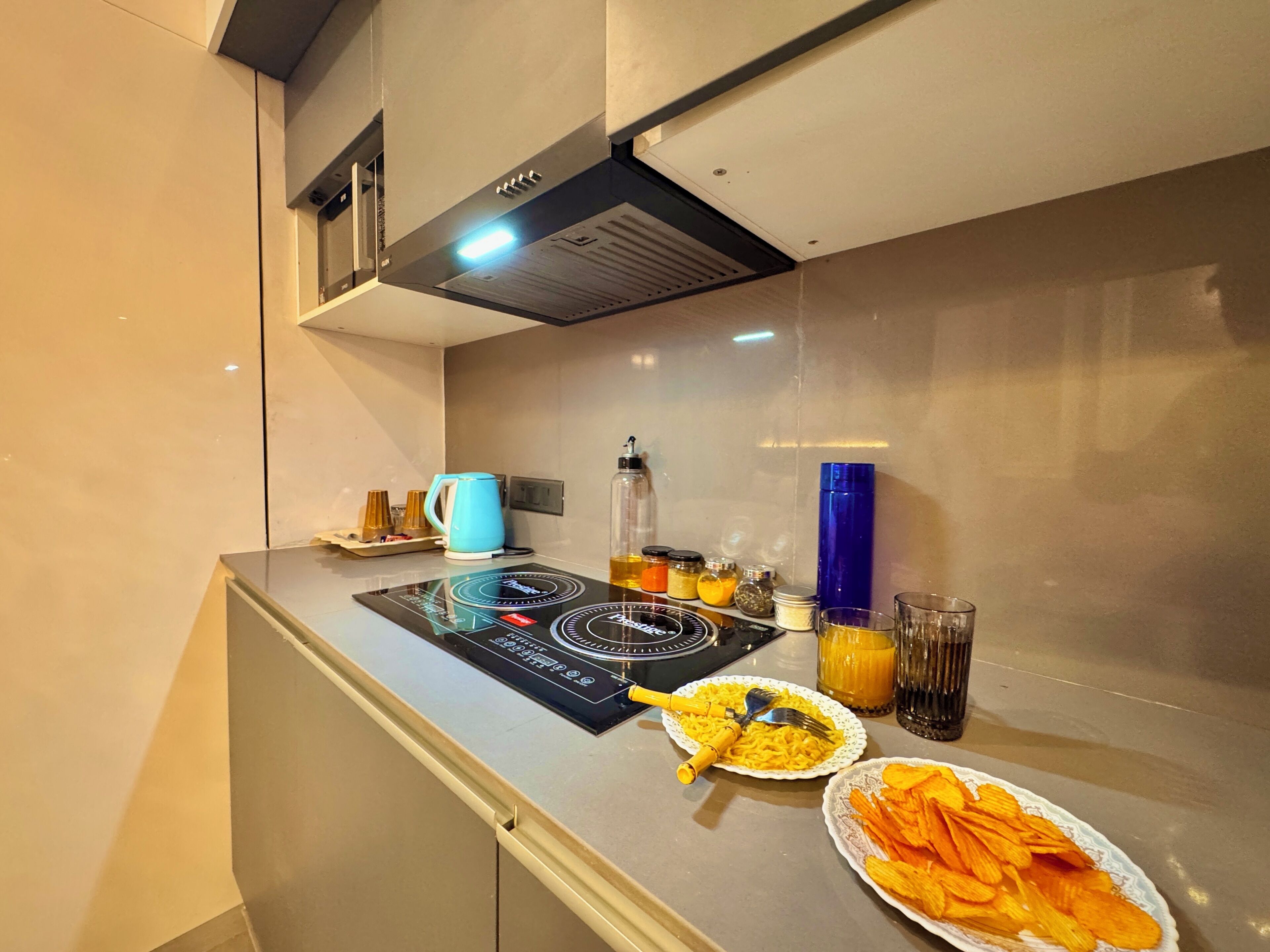 Una cocina moderna con una placa de inducción, un hervidor y diferentes condimentos en la encimera.