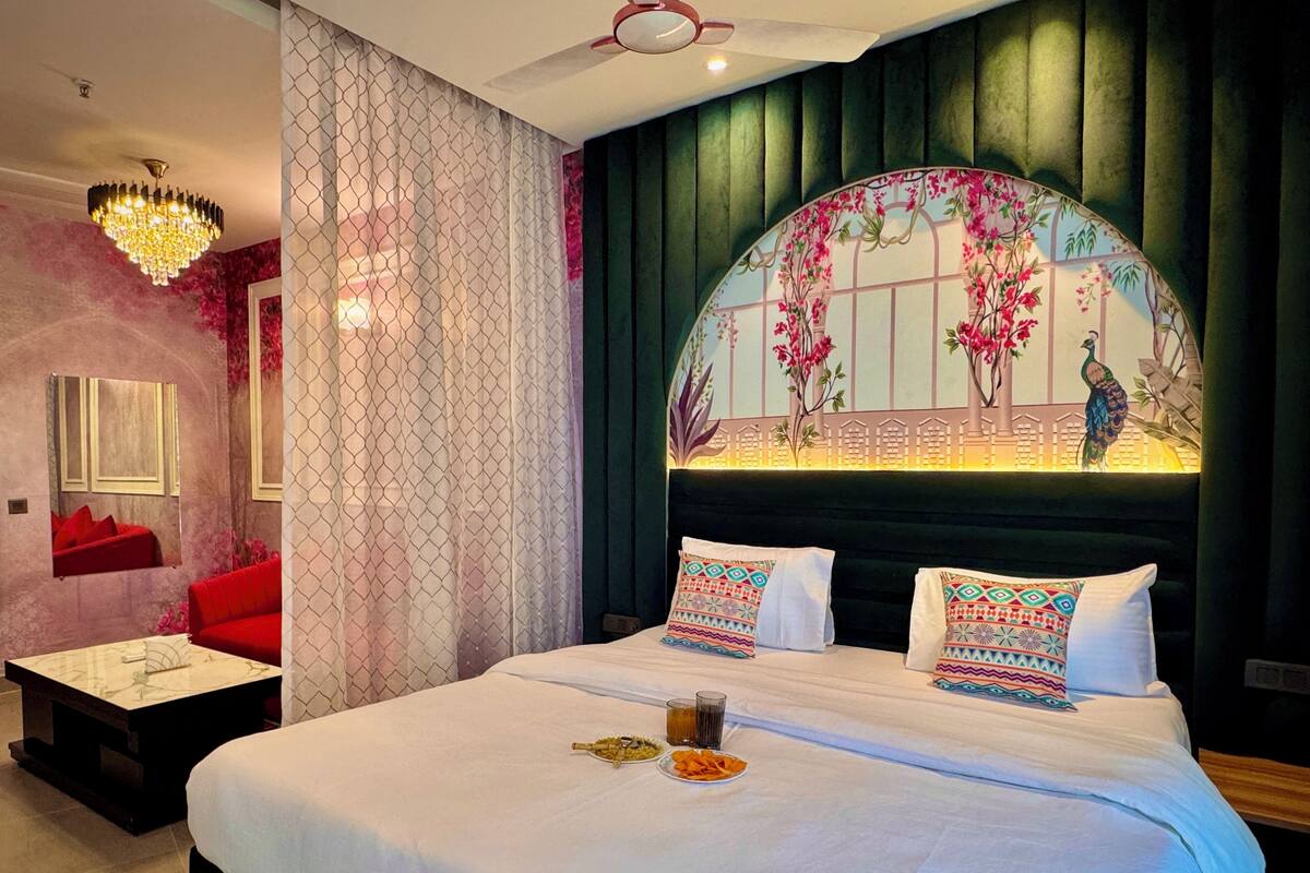 A bed with white linens, two pillows, a glass of water, and a plate of snacks.