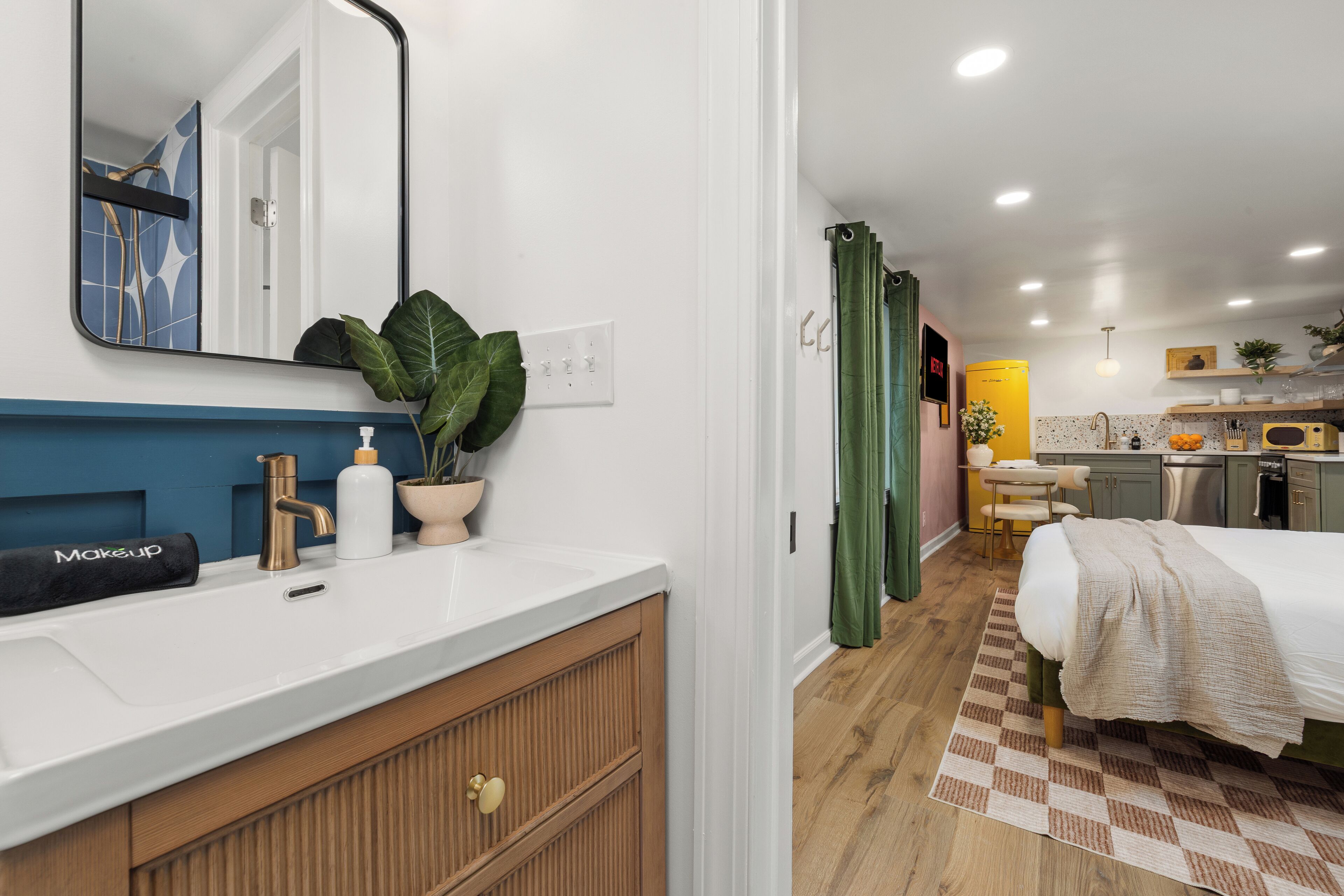 Un baño moderno con un lavabo blanco, un espejo y una planta en maceta.