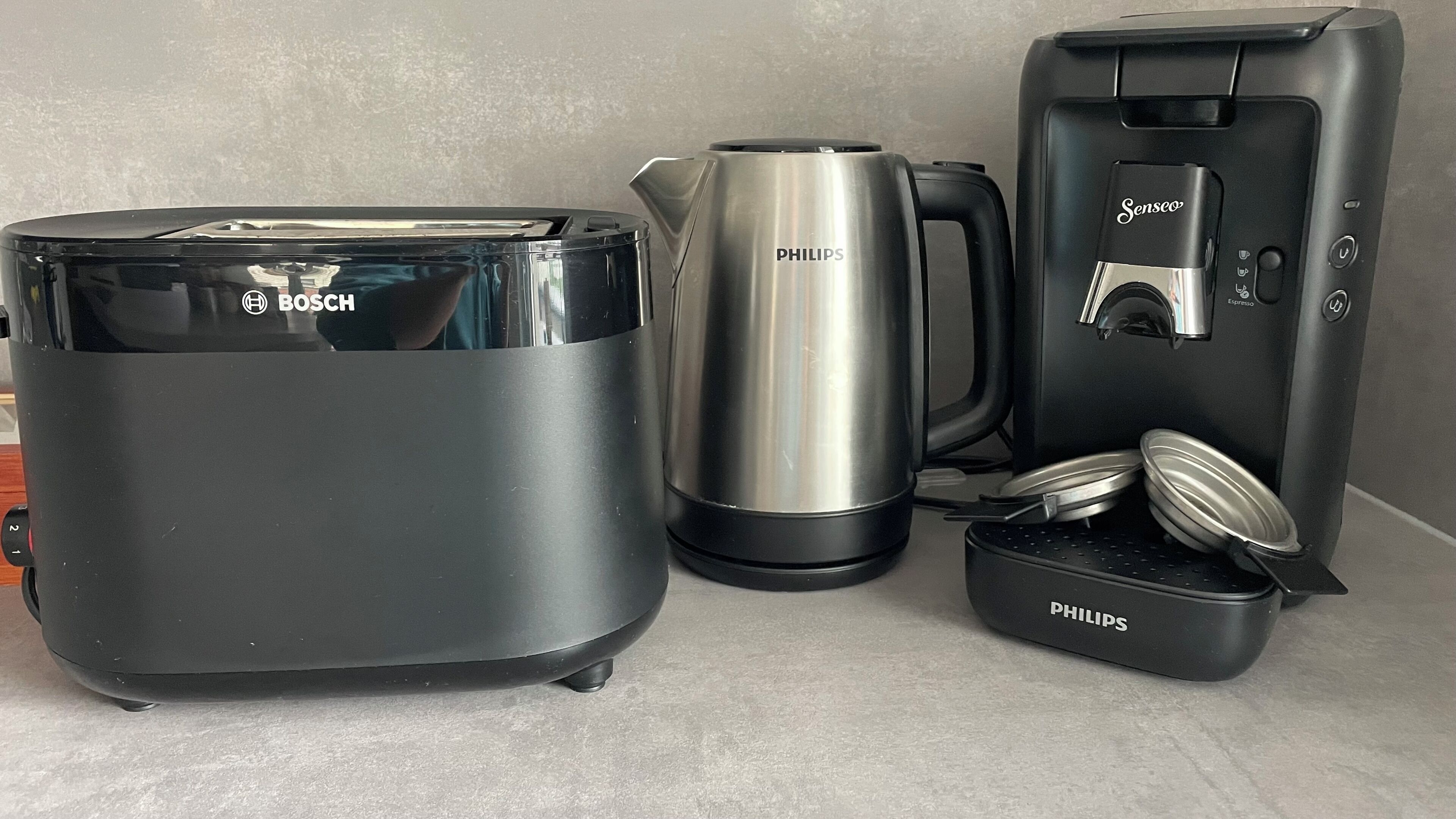 Un espacio tipo cocina con un tostador Bosch, una cafetera Philips y una máquina de café espresso Philips.