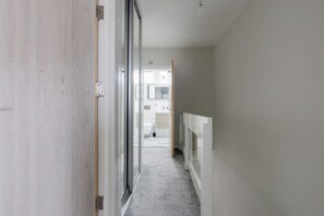 A hallway leading to a bathroom with a toilet, sink, and mirror. - Contemporary 3BDR Retreat in South West London (Greater London)