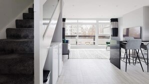 A modern interior with a staircase, a dining area, and a view through large windows. - Contemporary 3BDR Retreat in South West London (Greater London)