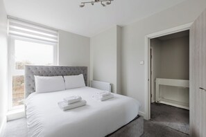 A bedroom with a bed, a radiator, a window, and an open closet. - Contemporary 3BDR Retreat in South West London (Greater London)