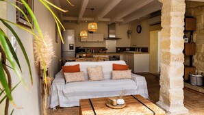 A cozy living area with a sofa, a coffee table, and a stone pillar. - Charming house in camargue private heated pool jacuzzi (Vauvert)