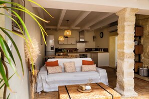 A cozy living area with a sofa, a coffee table, and a stone pillar. - Charming house in camargue private heated pool jacuzzi (Vauvert)