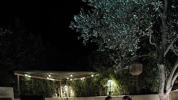 An outdoor seating area with a wicker lamp, a bucket with a bottle, and a candle on the floor. - Charming house in camargue private heated pool jacuzzi (Vauvert)