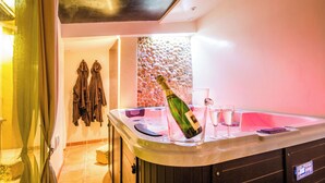A modern bathroom with a jacuzzi tub, a towel rack, and a bottle of champagne. - Charming house in camargue private heated pool jacuzzi (Vauvert)