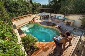 A backyard with a swimming pool, wooden deck, and outdoor seating area. - Charming house in camargue private heated pool jacuzzi (Vauvert)