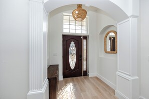 A hallway with a dark wooden door, a mirror, and a wicker chandelier. - The Azure Villa 5br 3.5 bath heated pool hot tub close to Gulf Beach Clearwater (Seminole)