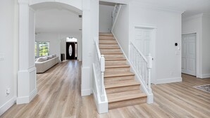 Ein geräumiger Flur mit einer Holztreppe, weißen Wänden und einer eingebauten Bank im Hintergrund.