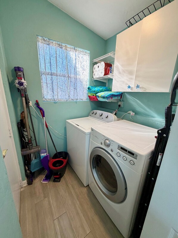 A laundry room with a washing machine, a vacuum cleaner, and a broom. - The Stillwater - Pool, Riverfront & Viewing Dock - Close to Speedway & Downtown! (Daytona Beach)
