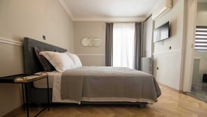 Un dormitorio con cama, mesita de noche, televisor montado en la pared y radiador.
