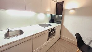 Una cocina compacta con lavamanos, estufa y microondas.