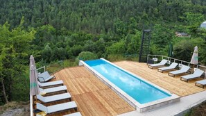 Una piscina al aire libre de temporada, sombrillas, tumbonas
