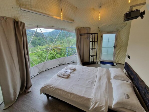 A bedroom with a bed, curtains, and a window overlooking a mountainous landscape. - Glamping Georgia - Krikhi  (Ambrolauri)
