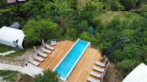 A cluster of dome-shaped accommodations surrounded by lush greenery, with a wooden deck and a pool area featuring sun loungers. - Glamping Georgia - Krikhi  (Ambrolauri)