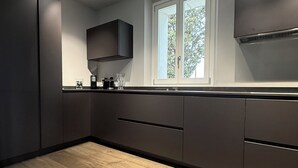Una cucina moderna con mobili scuri, una finestra e un pavimento in legno.