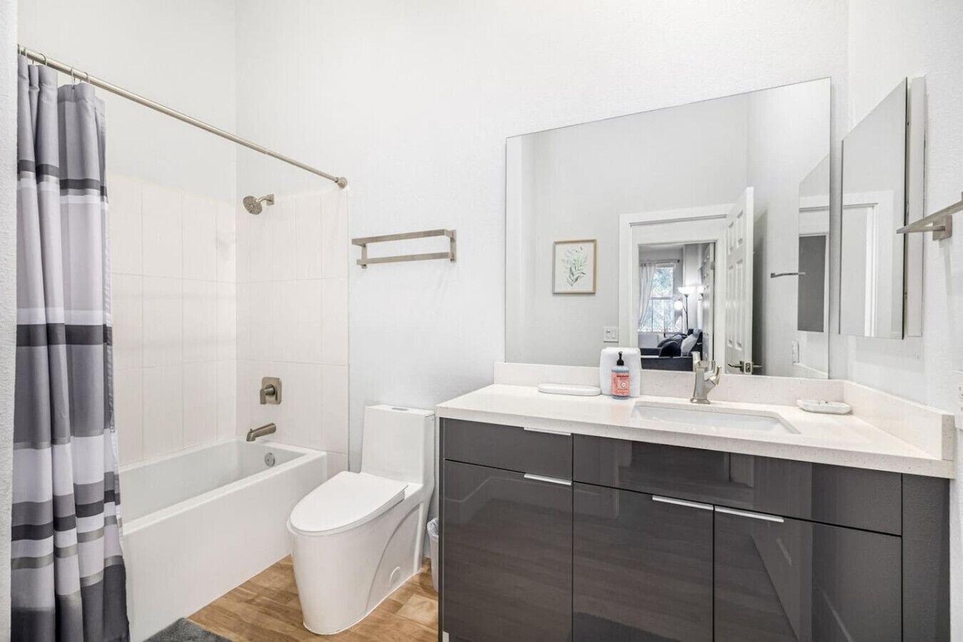 Een moderne badkamer met een badkuip, toilet en wastafel met een grote spiegel.