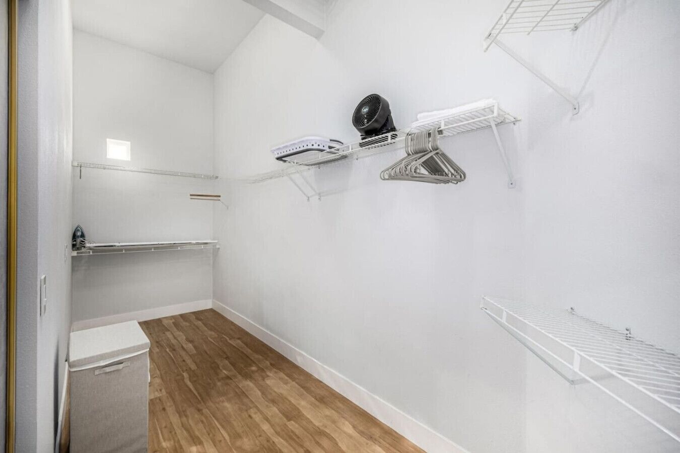 Ein kleiner Raum mit weißen Wänden und Holzboden, ein weißes Waschbecken sowie zwei Wäscheständer an der Wand.