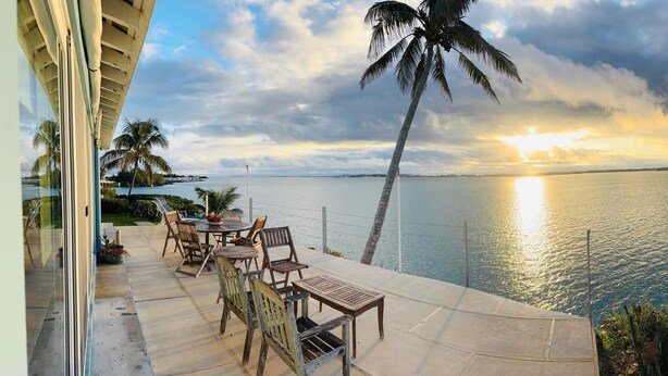 Un patio con mobiliario exterior con vistas a un cuerpo de agua al atardecer.