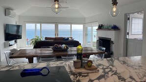 Una cocina moderna con una isla grande, un comedor con vistas al mar y una chimenea.
