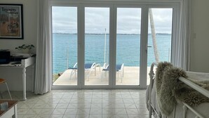 Una habitación con un gran ventanal corredero que da a un balcón con vistas al mar.