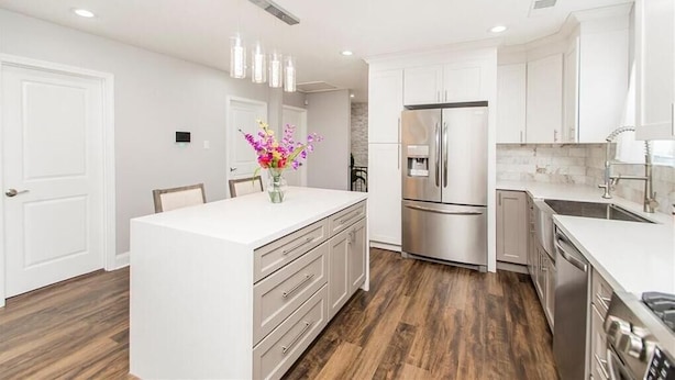 A modern kitchen with white cabinetry, stainless steel appliances, and a wooden floor. - Lovely, spacious & peaceful 3-bedroom house in New Orleans w AC & outdoor space. (New Orleans)