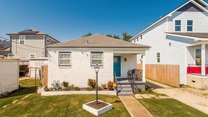A single-story house with a front door, a small porch, and a well-maintained lawn. - Lovely, spacious & peaceful 3-bedroom house in New Orleans w AC & outdoor space. (New Orleans)