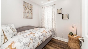 A bedroom with a bed, a ceiling fan, a wall-mounted light, and a framed certificate on the wall. - Lovely, spacious & peaceful 3-bedroom house in New Orleans w AC & outdoor space. (New Orleans)