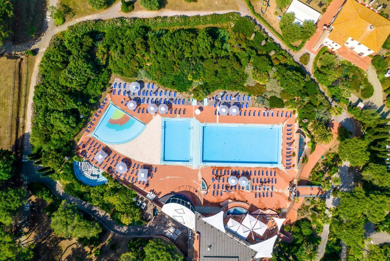 Vue aérienne d’un complexe hôtelier doté de plusieurs piscines, de chaises longues et d’un vaste espace paysager.