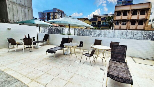 Une terrasse sur le toit avec des espaces de détente en plein air, comprenant des chaises et des tables, placés sous des parasols.