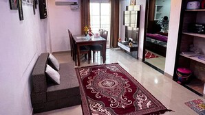 A compact living space with a dining area, a sofa, a chandelier, and a mirror. - Yashi Homestay Jaipur: A Peaceful Retreat in the Pink City (Jaipur)