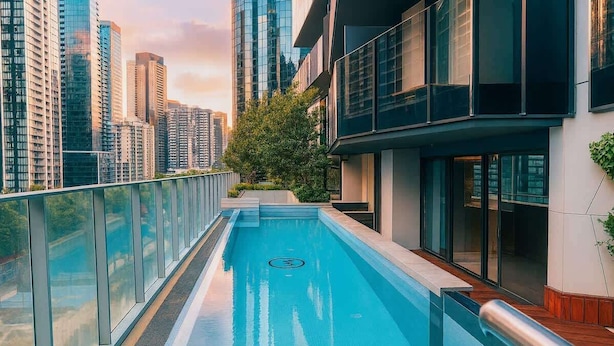 A modern building with a rooftop pool, surrounded by high-rise buildings and greenery. - Skyline Sanctuary | L35 Bay & City Views (Southbank)