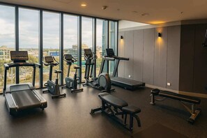 A modern gym with cardio machines, weight benches, and a large window offering a city view. - Skyline Sanctuary | L35 Bay & City Views (Southbank)