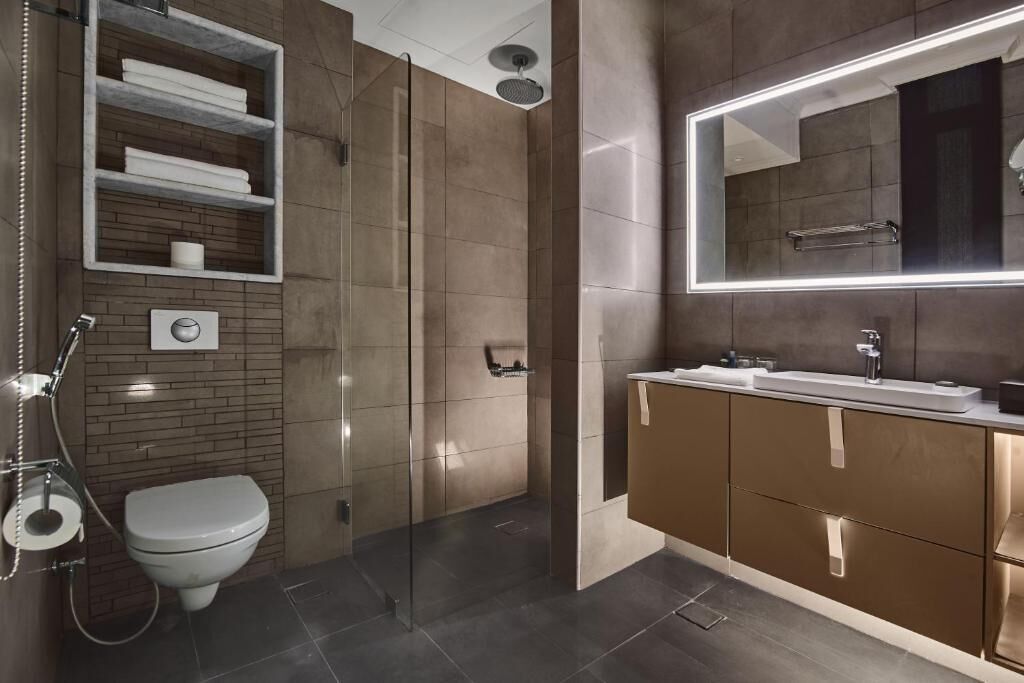 A modern bathroom with a glass-enclosed shower, a toilet, and a vanity with a large mirror.