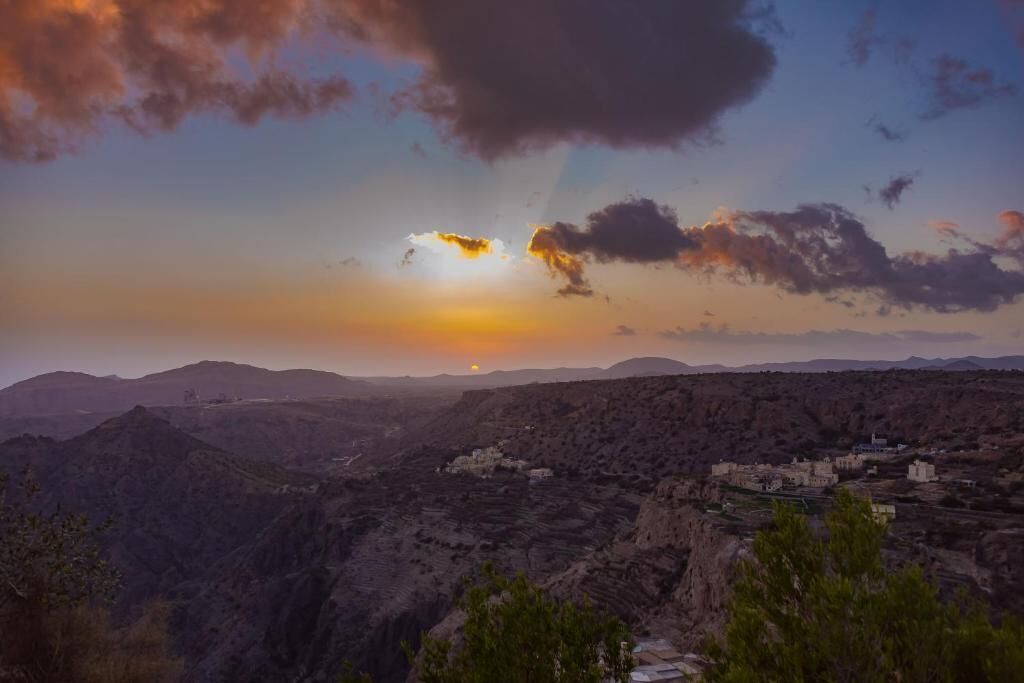 Paisaje montañoso con un pueblo al atardecer.