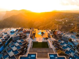 Un resort con varias piscinas, un patio central y montañas al fondo.