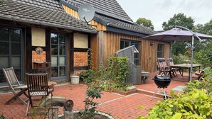 Eine Ziegelterrasse mit Gartenmöbeln, einem Grill und einer Sat-Schüssel.