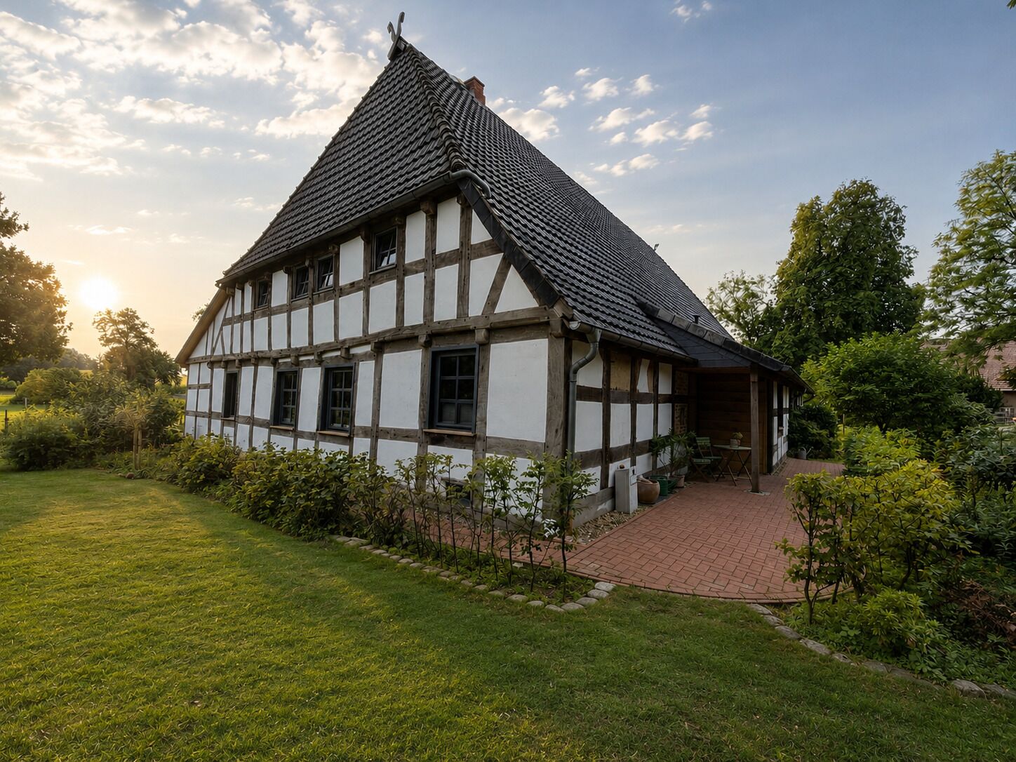 Ein traditionelles Fachwerkhäuschen mit einem steilen Satteldach, umgeben von einem gepflegten Garten und einem gepflasterten Weg.