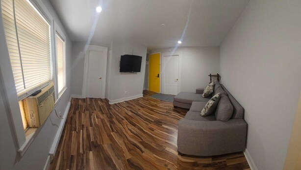A modern living room with a grey sofa, wooden flooring, and a TV mounted on the wall. - Perfect 3-bedroom apartment  in  Waterbury CT (Waterbury)
